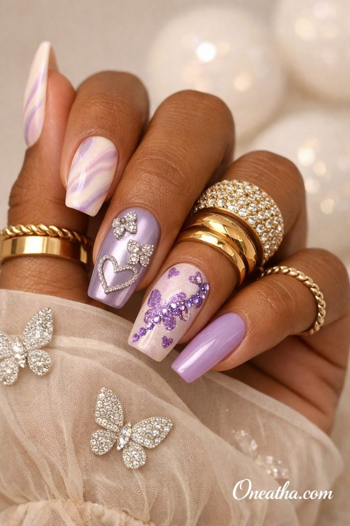 Lilac purple butterfly nails with chrome finish, ombre accents, rhinestone butterfly and heart nail art, glossy square acrylic nails on warm-toned hand with gold rings, luxury nail inspiration