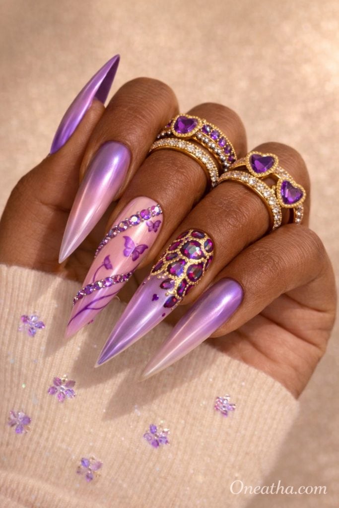 Purple butterfly nails with lilac chrome finish, nude base, rhinestone accents, gold detailing, glossy stiletto acrylic nails featuring butterfly nail art on a warm-toned hand with gold rings, luxury nail inspiration