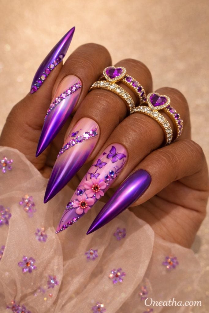 Purple butterfly nails with chrome finish, nude ombre base, floral nail art, rhinestone accents, glossy stiletto acrylic nails on warm-toned hand with gold rings, luxury nail inspiration