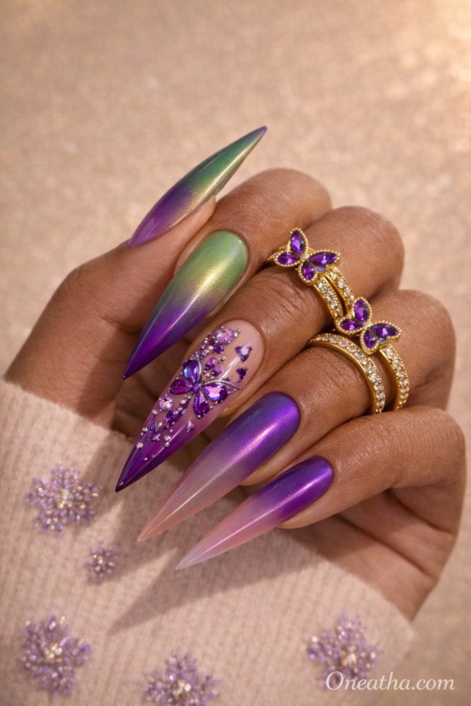 Purple butterfly nails with chrome ombre gradient, green and purple shimmer nails, rhinestone butterfly nail art, glossy stiletto acrylic nails, luxury nail design on warm-toned hand with gold rings