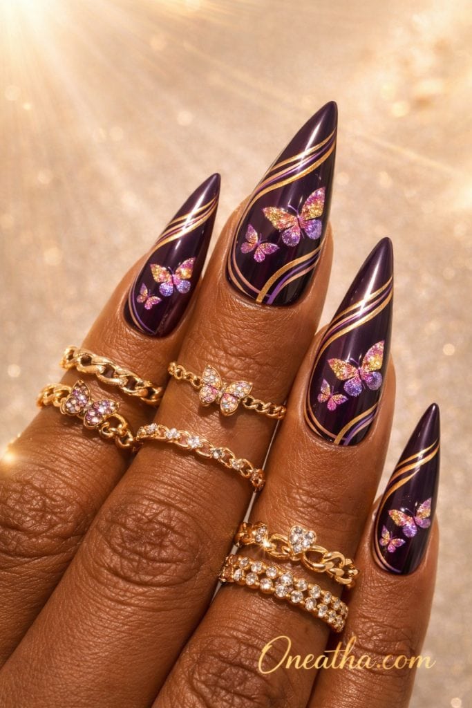 Glossy deep purple butterfly nails with gold swirl accents and glitter butterfly designs on stiletto-shaped nails, luxury manicure inspiration with warm-toned hand and gold rings