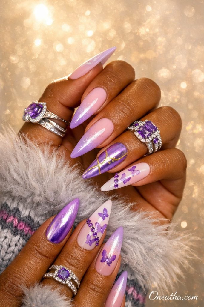 Lilac purple butterfly nails with chrome, ombre pink and purple gradient, glossy stiletto nails with butterfly designs and rhinestones on a warm-toned hand with silver rings