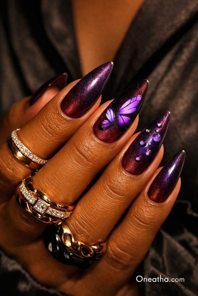 Dark purple butterfly nails with chrome cat eye effect, burgundy shimmer nails, glossy almond acrylic nails, butterfly nail art accent, luxury nail design on warm-toned hand with gold rings
