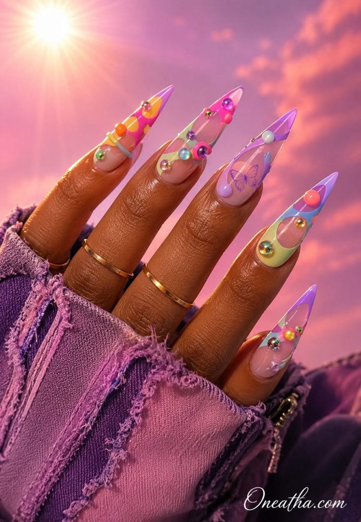 Pastel stiletto nails with a subtle purple butterfly and colorful gemstones.