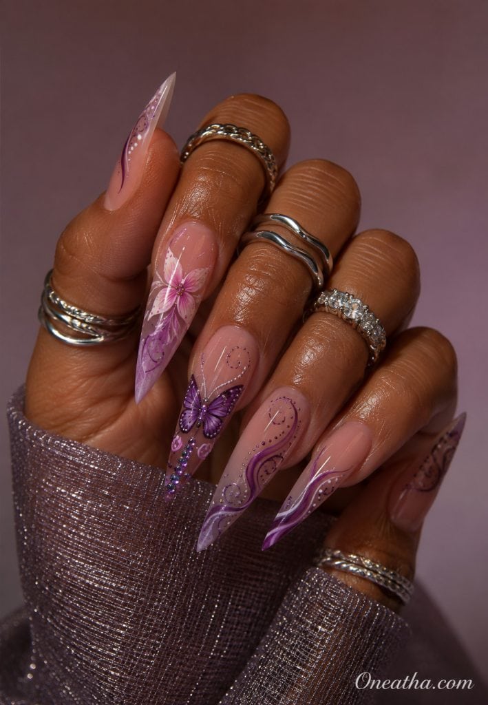Lavender butterfly stiletto nails with floral accents.