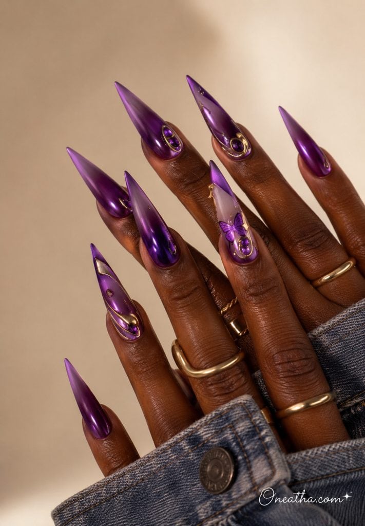 Purple chrome stiletto nails with gold accents and jewels.