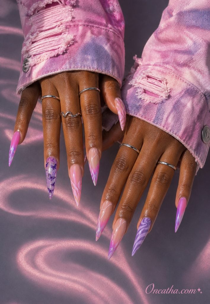 Pink swirl stiletto nails with a purple butterfly accent nail.