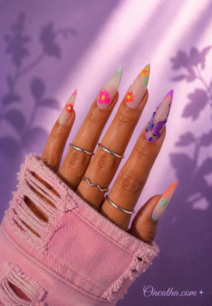Matte pastel stiletto nails with colorful florals and a purple butterfly accent nail.