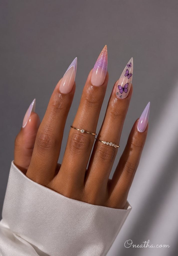 Warm cinnamon-toned hand model with sunset shimmer stiletto nails and a lilac butterfly accent nail.