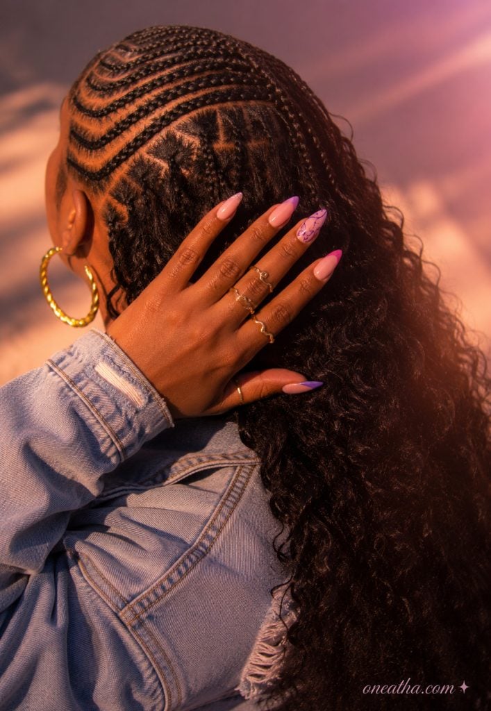 Curly braided hairstyle with purple butterfly nails.