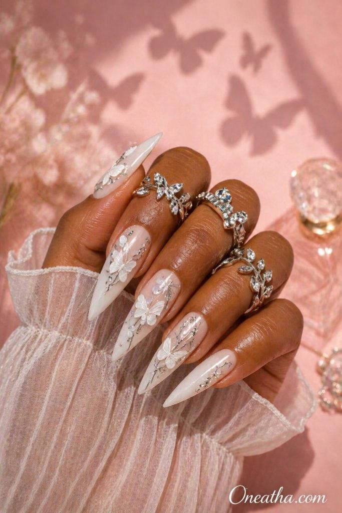 Butterfly stiletto nails by Oneatha featuring luxury silver accents and white butterfly nail art on long glossy acrylic nails.