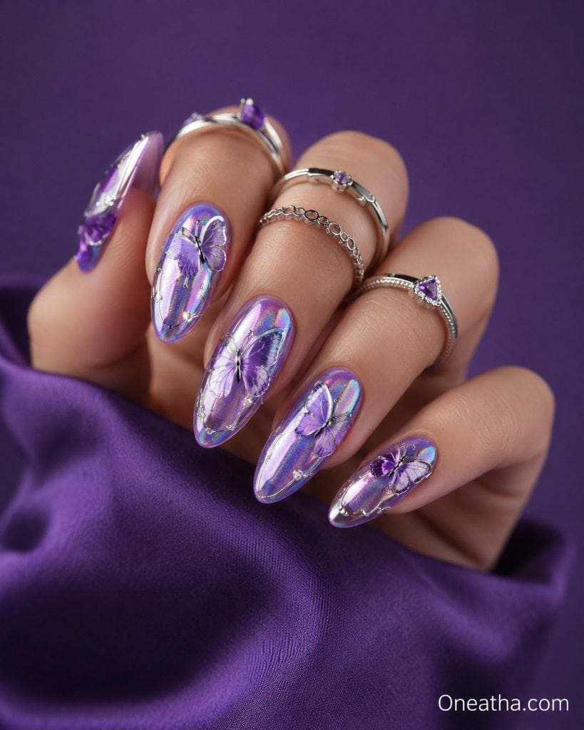 Luxury purple chrome aura butterfly nails with holographic shimmer on long almond-shaped nails, featuring translucent lavender butterfly nail art, glossy reflective finish, silver rings, and deep violet satin styling. High-fashion editorial nail photography by Oneatha showcasing elegant butterfly nails, chrome nails, lavender nails, aura nails, and luxury nail inspiration.
