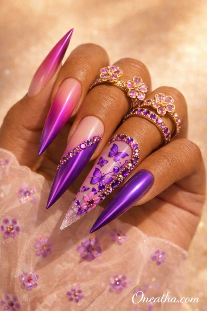 Luxury purple chrome butterfly nails on a warm cinnamon-toned hand model featuring hot pink to purple ombré nails, amethyst gemstones, butterfly nail art, floral nail designs, gold flower rings with pink gemstones, and a sheer pink floral blouse. Sunlit beige luxury beauty photography showcasing glamorous purple nail inspiration by Oneatha, Oneatha.com.