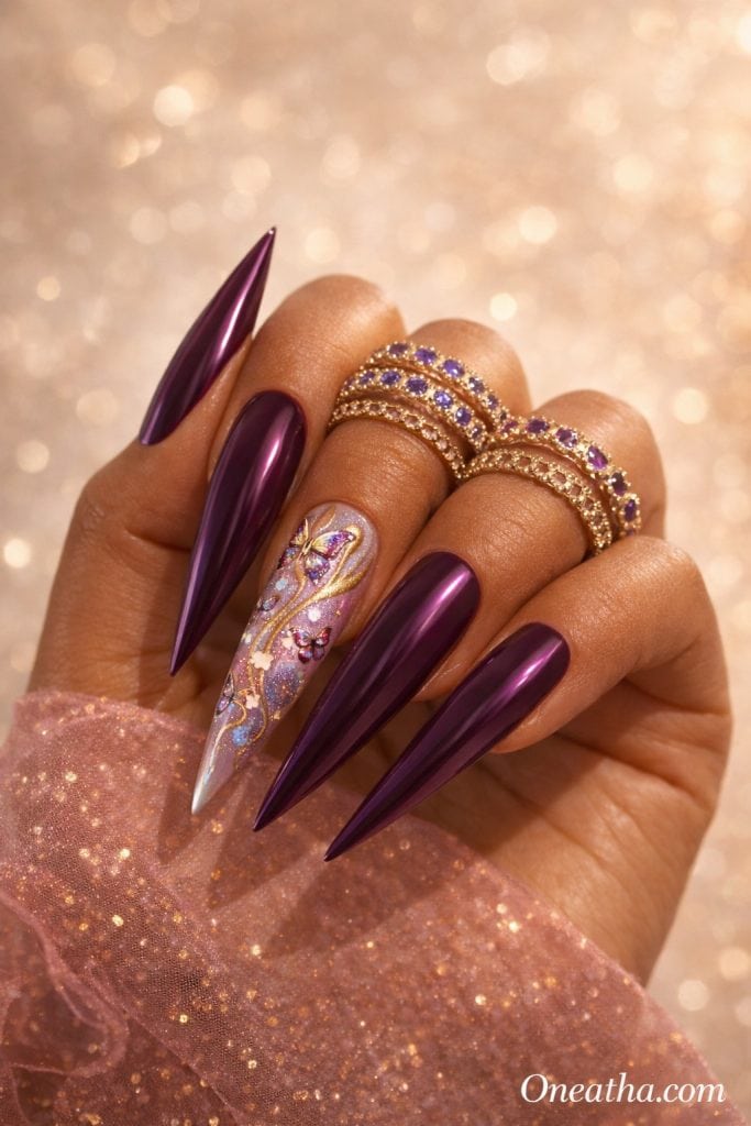 Deep plum chrome stiletto butterfly nails with gold shimmer accents, purple and gold ombré butterfly nail art, glitter details, luxury nail design, long stiletto nails, feminine summer nails, fantasy-inspired butterfly manicure on a warm cinnamon-toned hand model with gold gemstone rings, luxury beauty editorial by Oneatha.