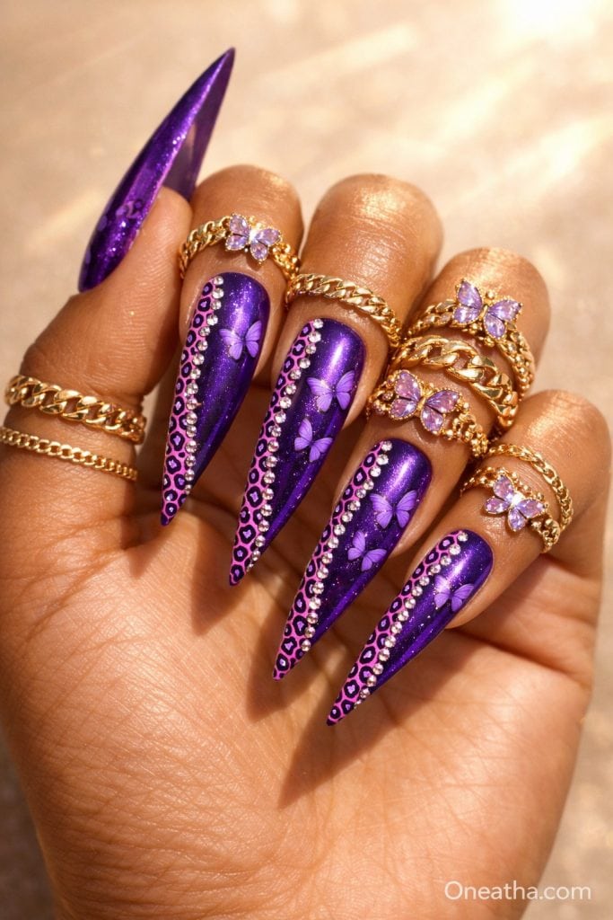 Oneatha Butterfly luxury deep plum purple chrome nails featuring butterfly nail art, pink and white leopard print detailing, sparkling gemstone accents, almond-shaped nails, glamorous purple manicure, gold jewelry styling, luxury butterfly nails, chrome purple nail design, feminine nail inspiration, high-end gemstone nail art, Oneatha signature nail collection.