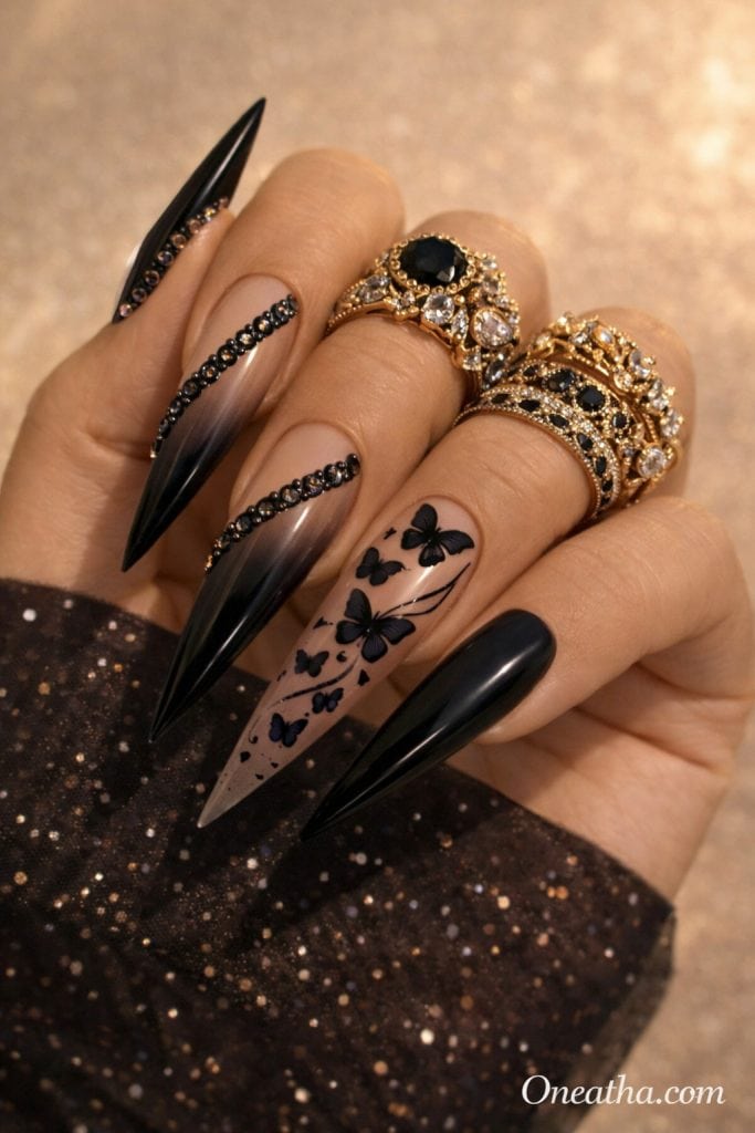 Black butterfly nails with nude to black Ombre base, glossy finish, and rhinestone accents on long stiletto nails. Elegant black butterfly nail design with soft gradient detail and a luxury high-shine look.