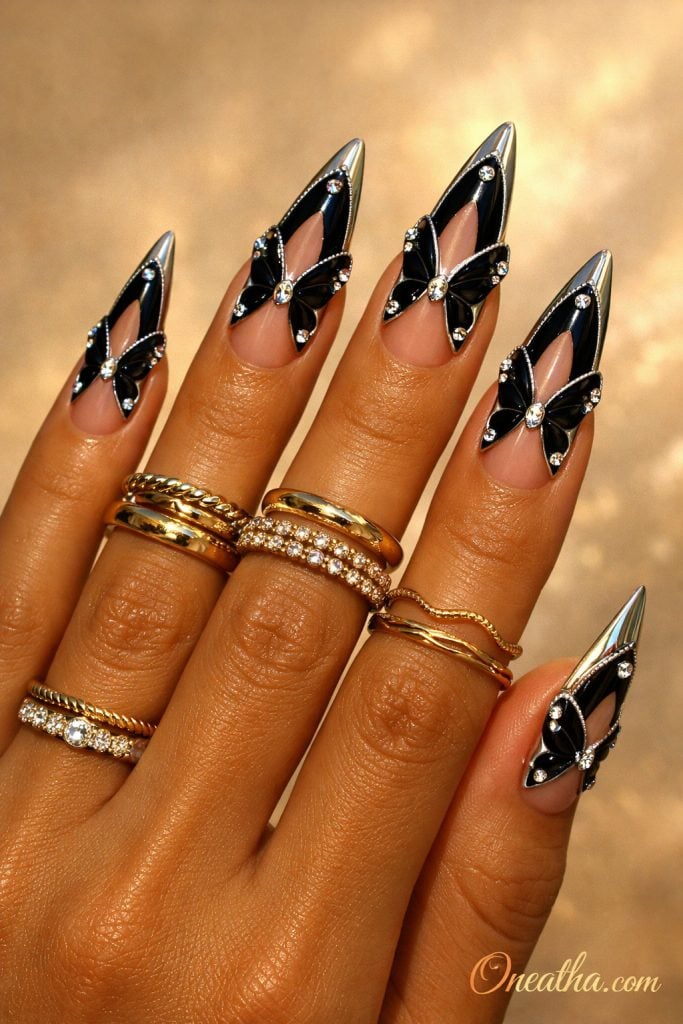 Black butterfly French tip nails with chrome edges and crystal rhinestone accents on long stiletto nails. Glossy black butterfly nail design with a luxe finish and high-shine detailing.