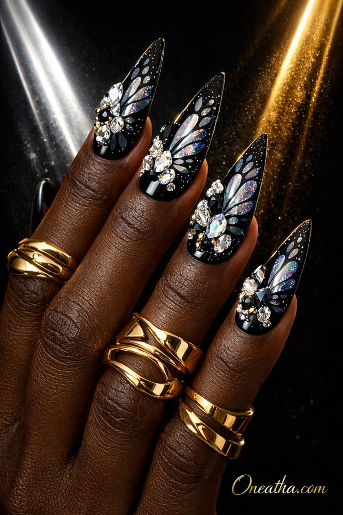 Black butterfly nails with crystal rhinestone accents and iridescent wing detailing on long stiletto nails. Glamorous black butterfly nail design with high shine, sparkle, and luxury embellishments.