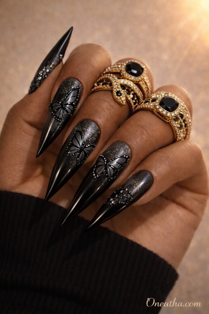 Black butterfly nails with chrome shimmer finish and glitter dust overlay on long stiletto nails. Glossy black butterfly nail design with a luxury aesthetic, sparkle gradients, and high-shine detail.
