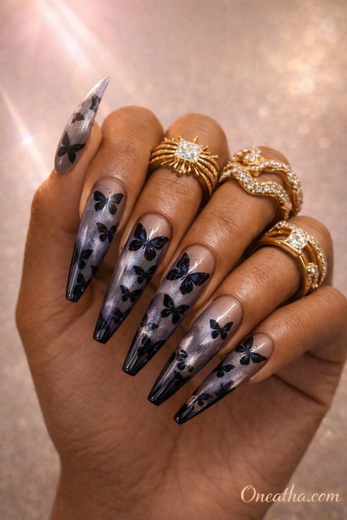 Smoky ombre butterfly nails with gray, purple, and silver tones featuring black butterfly designs on long almond nails. Glossy butterfly nail design with soft gradient blending and a luxe, glowing finish.