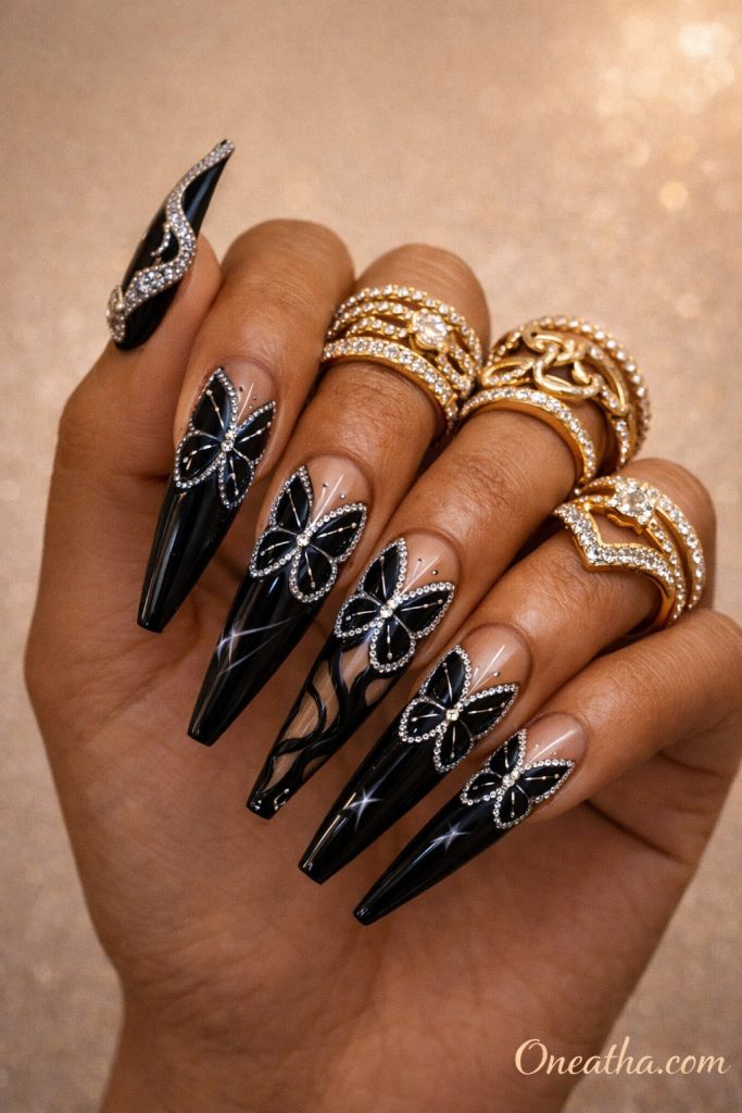 Black butterfly nails with silver rhinestone outlines and metallic accents on glossy coffin-shaped nails. Elegant black butterfly nail design with high shine, crystal detailing, and a luxury finish.