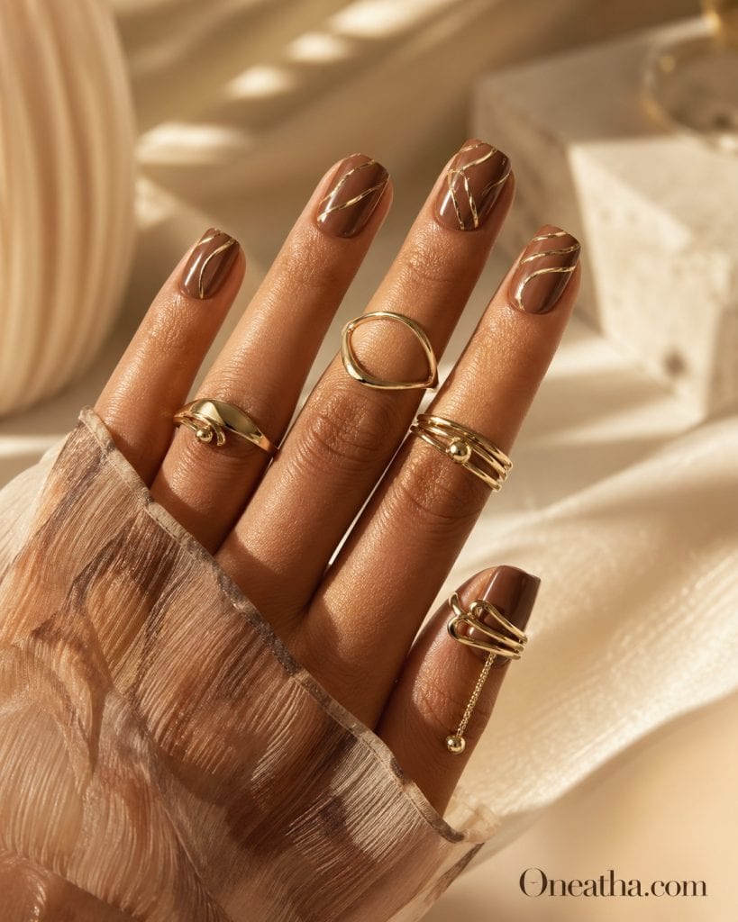 Brown luxe nails with gold chrome line detailing, glossy brown manicure with elegant metallic accents, luxury square nail design, high-end nail art inspiration with dimensional glow and modern classy aesthetic.