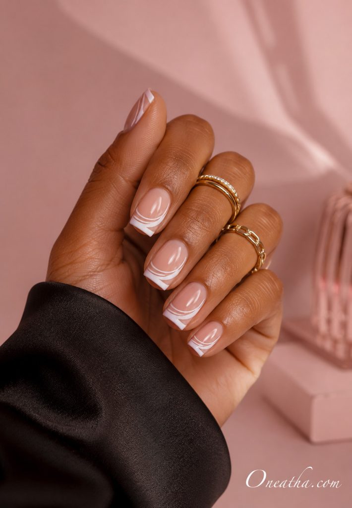 Elegant swirl French tip nails featuring graceful curved designs over a glossy nude base, creating a chic and eye-catching manicure.