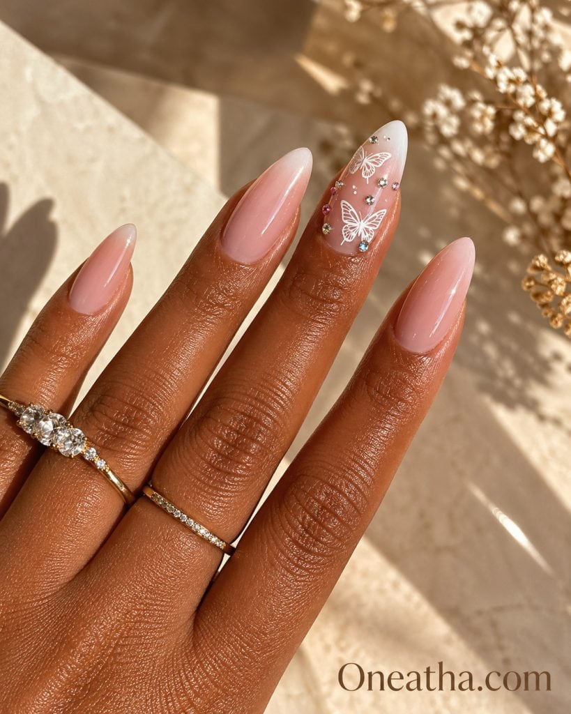 Butterfly nail designs by Oneatha featuring summer luxe butterfly nails with sheer nude bases, pink and silver rhinestone accents, and elegant minimal styling for a classic yet powerful seasonal nail look.