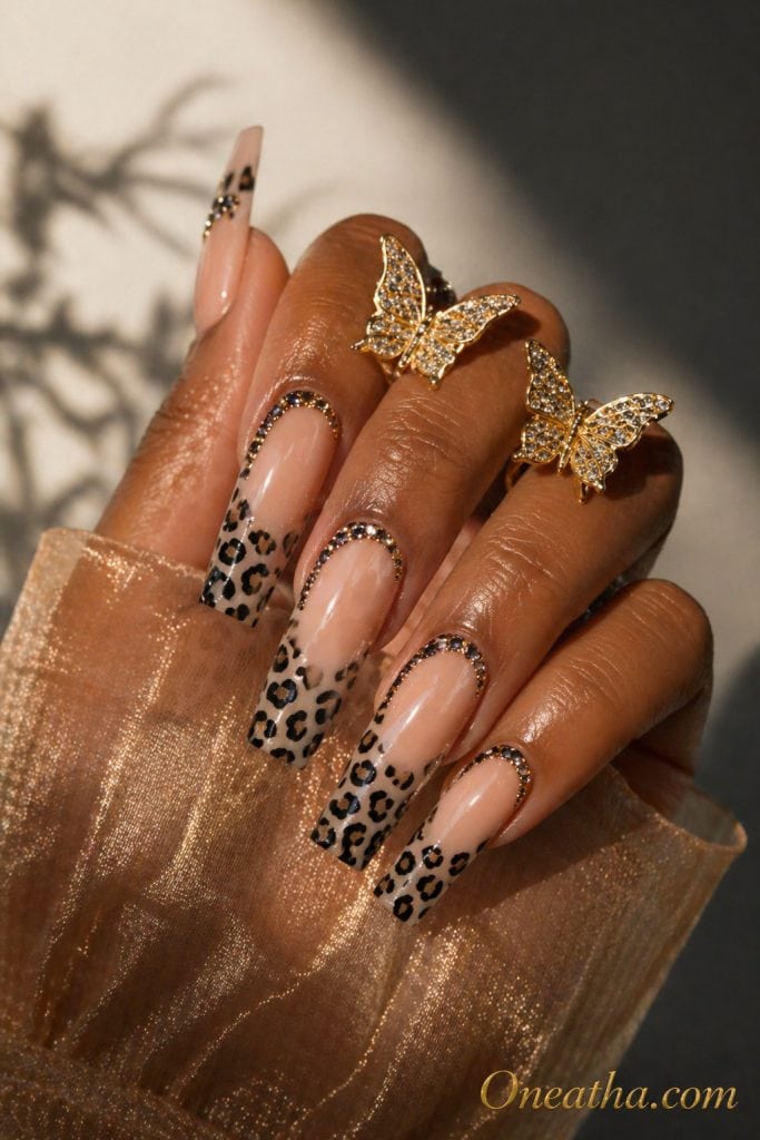 Nails by Oneatha featuring glamorous leopard print nails with bold black and nude patterns, sparkling rhinestones at the base, glossy finish, and an everyday luxe aesthetic.