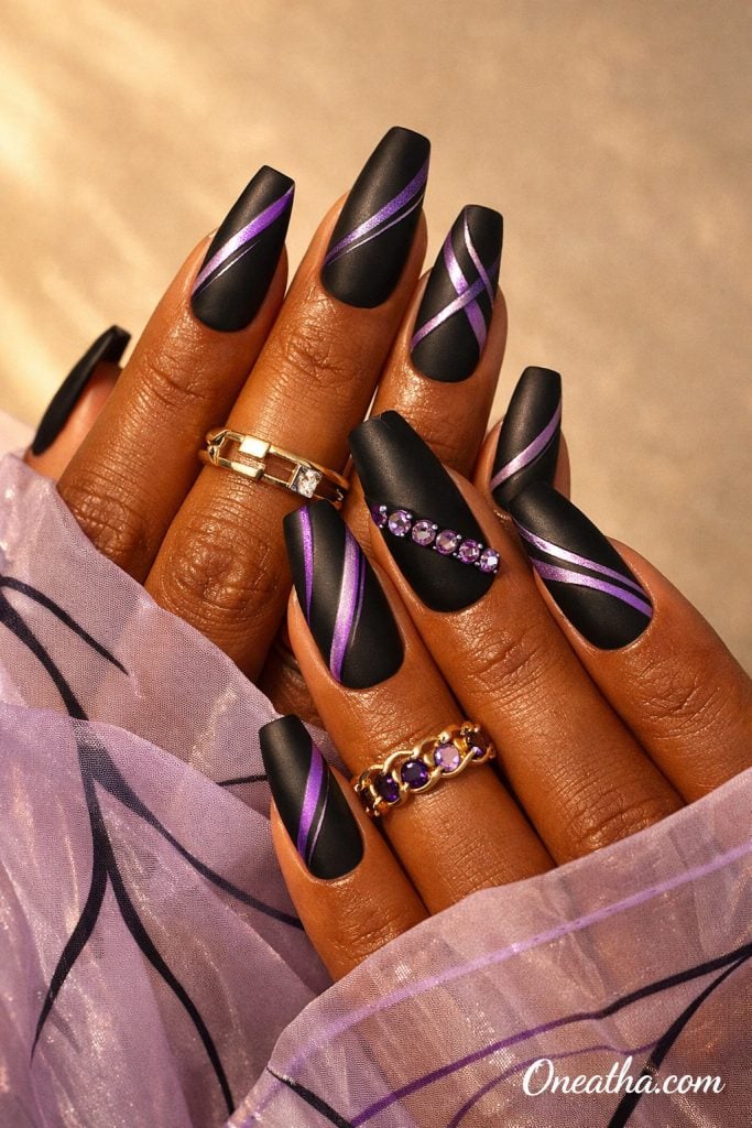 Oneatha Purple Luxe Nails featuring matte black nails with purple line nail art, purple gemstone accent nail, luxury nail design, elegant black and purple nails, glamorous manicure inspiration, stylish nail art.