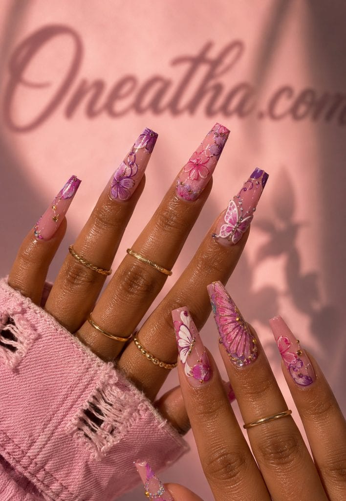 Pink butterfly floral nails with glossy luxury nail art.