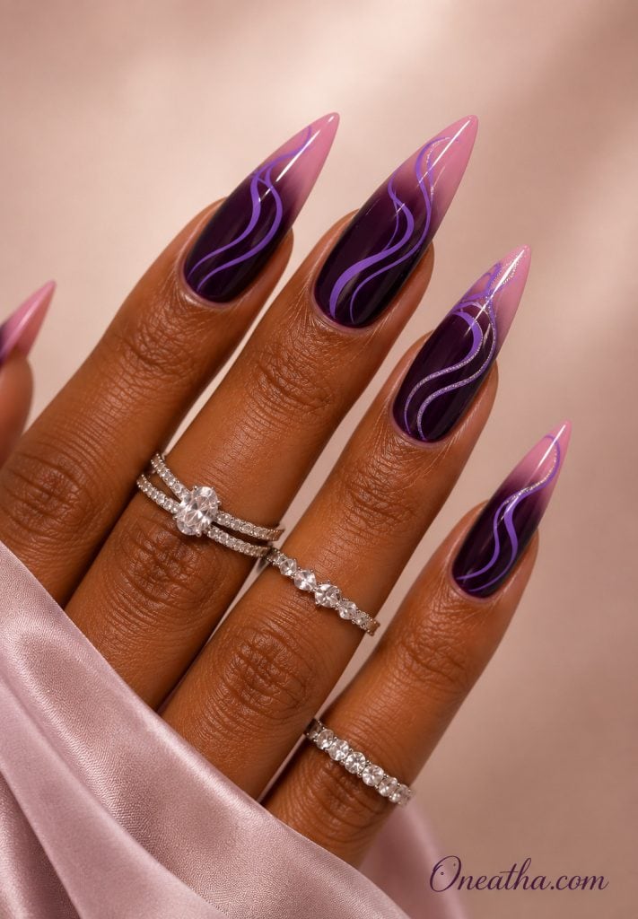Glossy almond nails by Oneatha featuring a deep blackberry purple ombré fading into soft blush pink tips with flowing lilac swirl line art, styled with sparkling silver rings and a blush satin sleeve against a luxury neutral background.