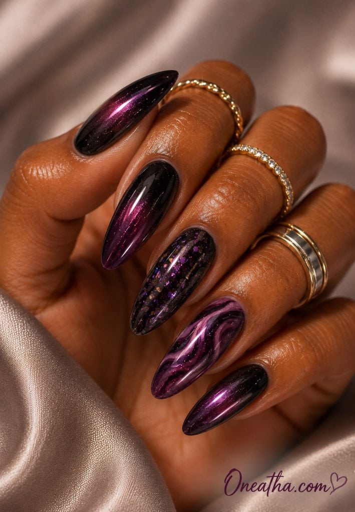 Glossy almond nails by Oneatha featuring deep blackberry chrome polish, black-to-plum ombré nails, a purple glitter accent nail, and a black and plum marble swirl accent, styled with elegant gold rings against a soft satin luxury background.
