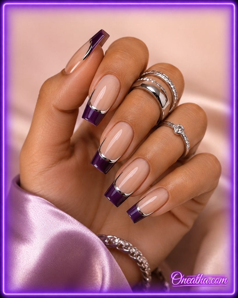 Glossy square French tip nails by Oneatha featuring deep royal purple tips, sleek silver chrome accent lines, a sheer nude base, silver statement rings, and a lilac satin sleeve against a soft luxury background.