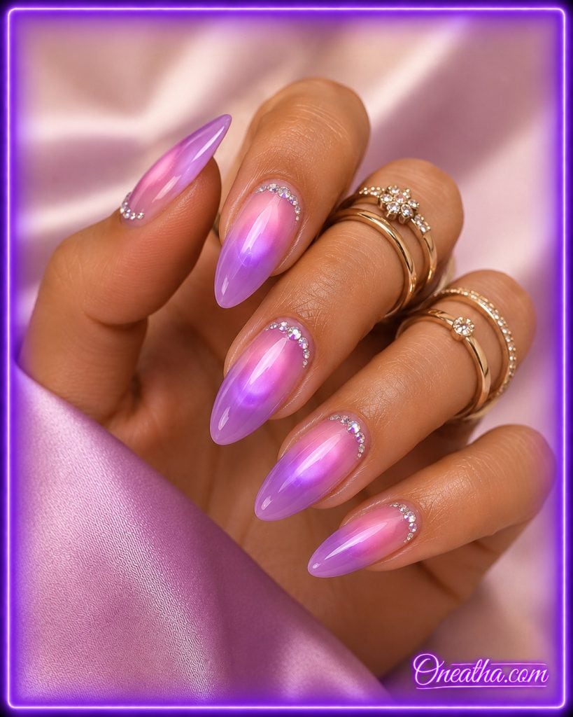 Glossy almond aura nails with a pink and lilac chrome gradient and crystal cuticle accents by Oneatha.