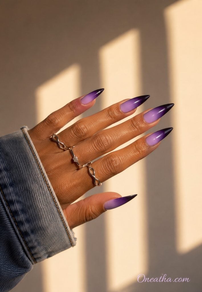 Glossy lilac-to-plum ombré almond nails in warm golden light by Oneatha.