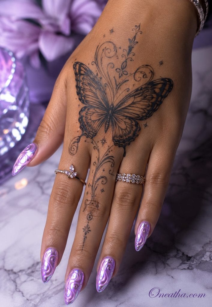 Glossy lilac chrome swirl nails by Oneatha featuring flowing artistic line details, almond-shaped nails, a butterfly hand tattoo, silver rings, and a luxurious editorial finish.